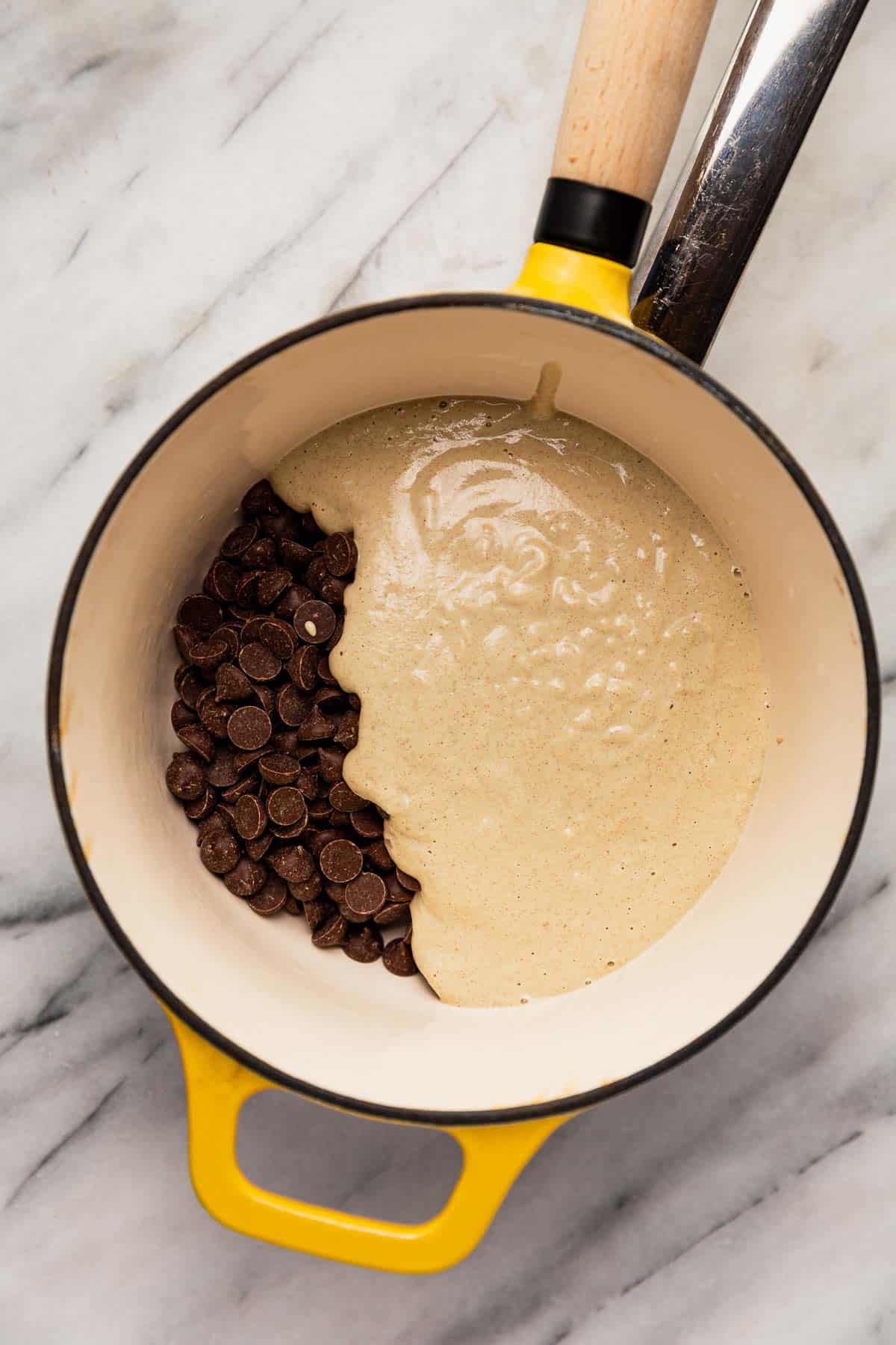 Chocolate and vegan cream in an enameled pot to melt for homemade chocolate rosemary truffles.