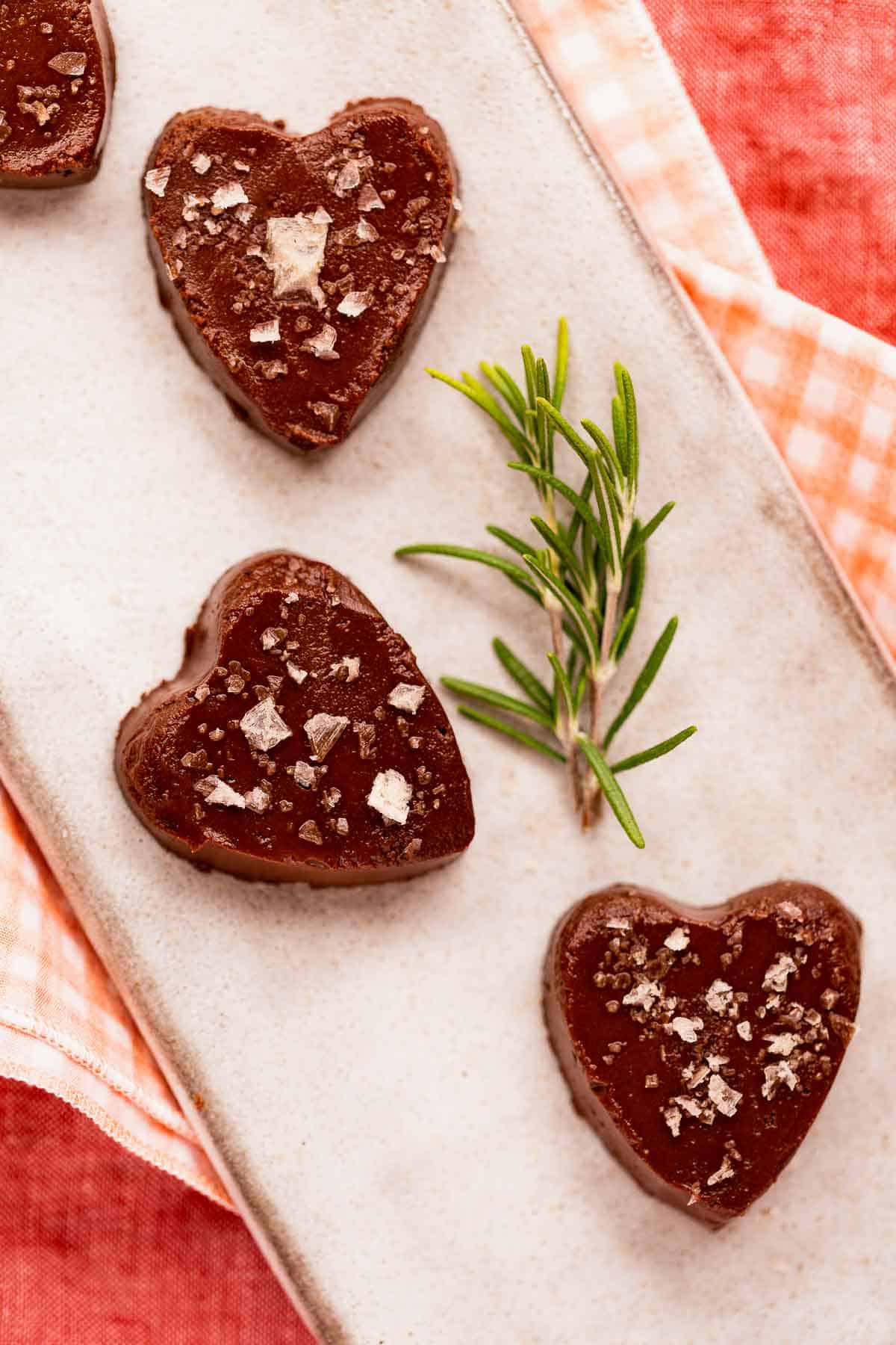 A closeup of homemade vegan chocolate rosemary truffles on a long plate.