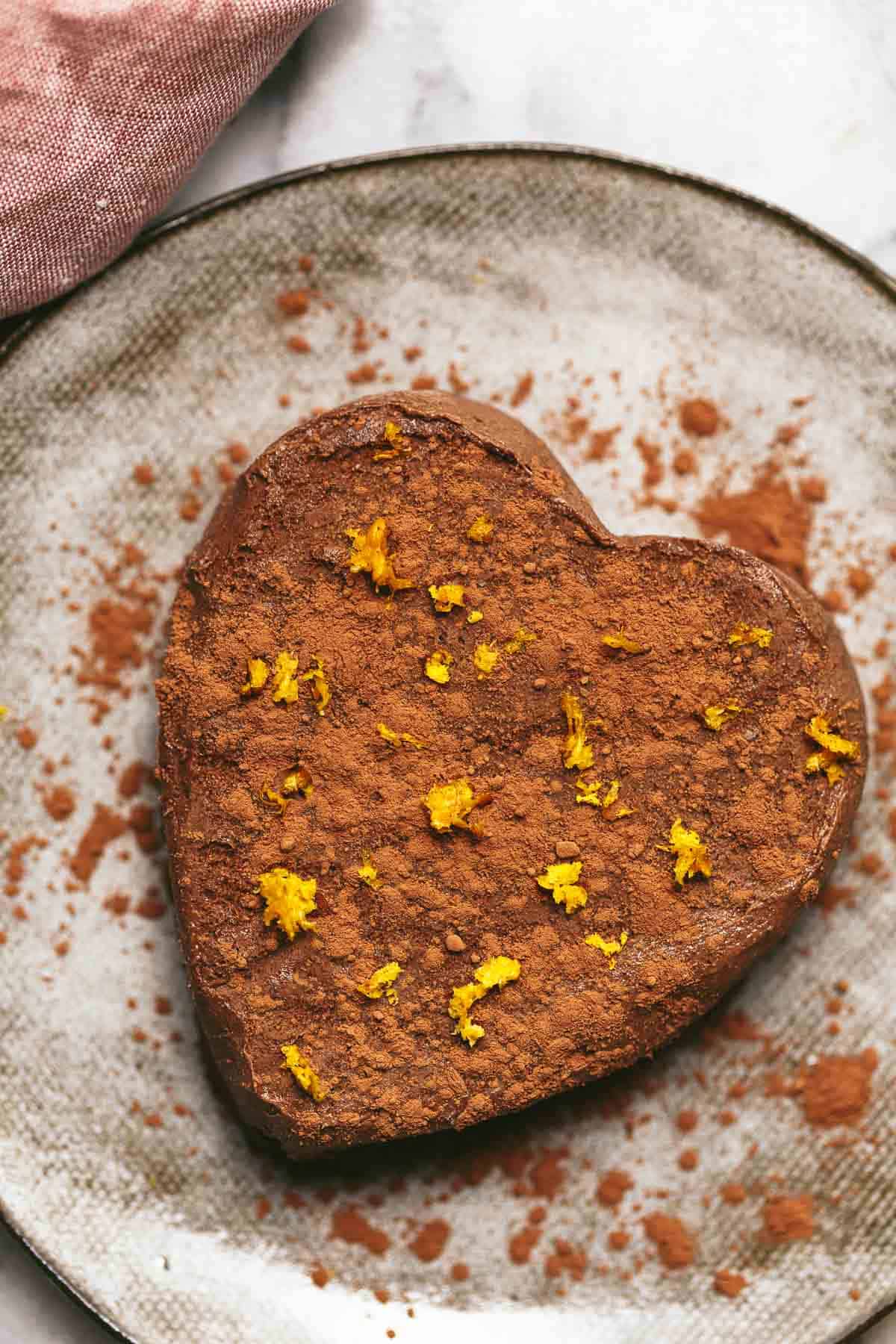 A heart-shaped vegan chocolate orange semifreddo sized for two on a plate, topped with orange zest.