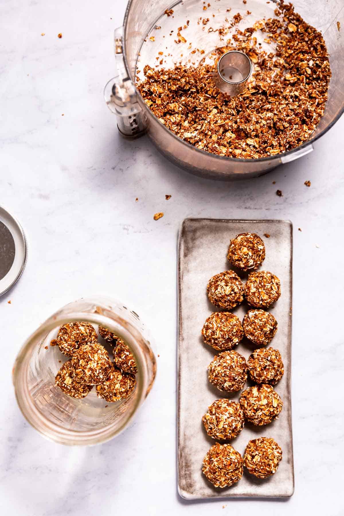 Chocolate orange energy balls on a long serving plate, with processed ingredients in a food processor and finished balls in a jar.