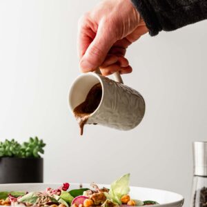 tahini-balsamic dressing poured onto a colorful salad