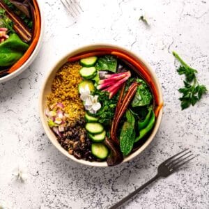 A bowl full of colorful veggies, golden curry quinoa, and black beans.