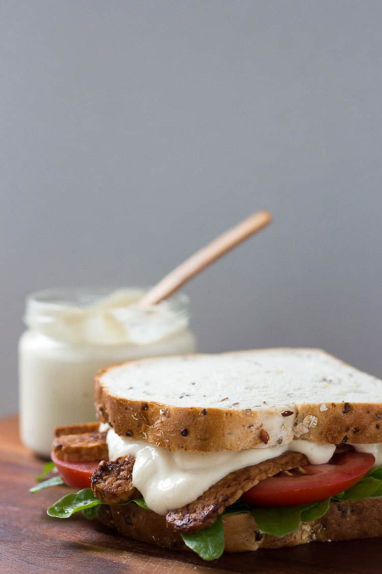 A sandwich with lots of homemade mayo on it, with a jarful of mayo behind it.