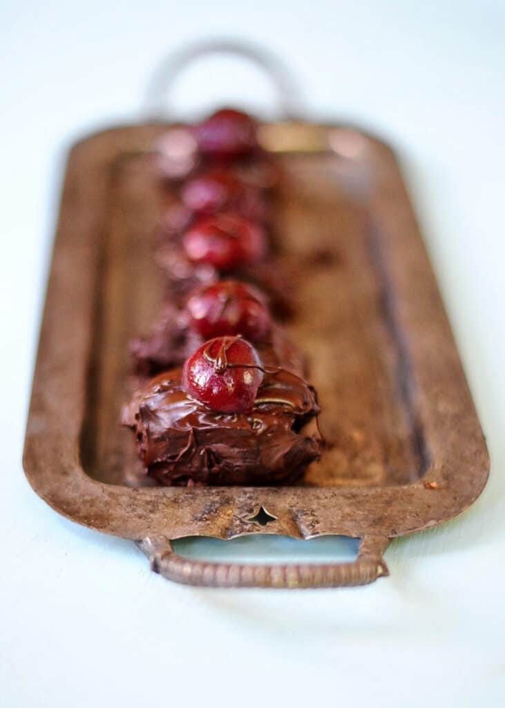 chocolate bon bons lining a tray with a cherry on top