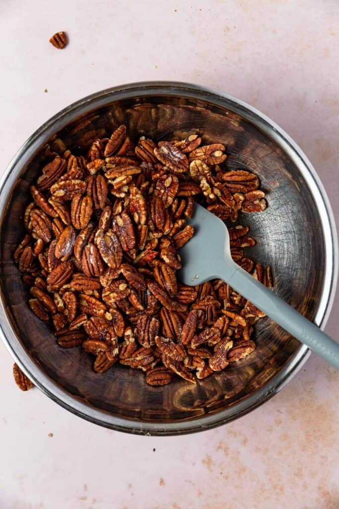 A bowl of pecans mixed with maple syrup