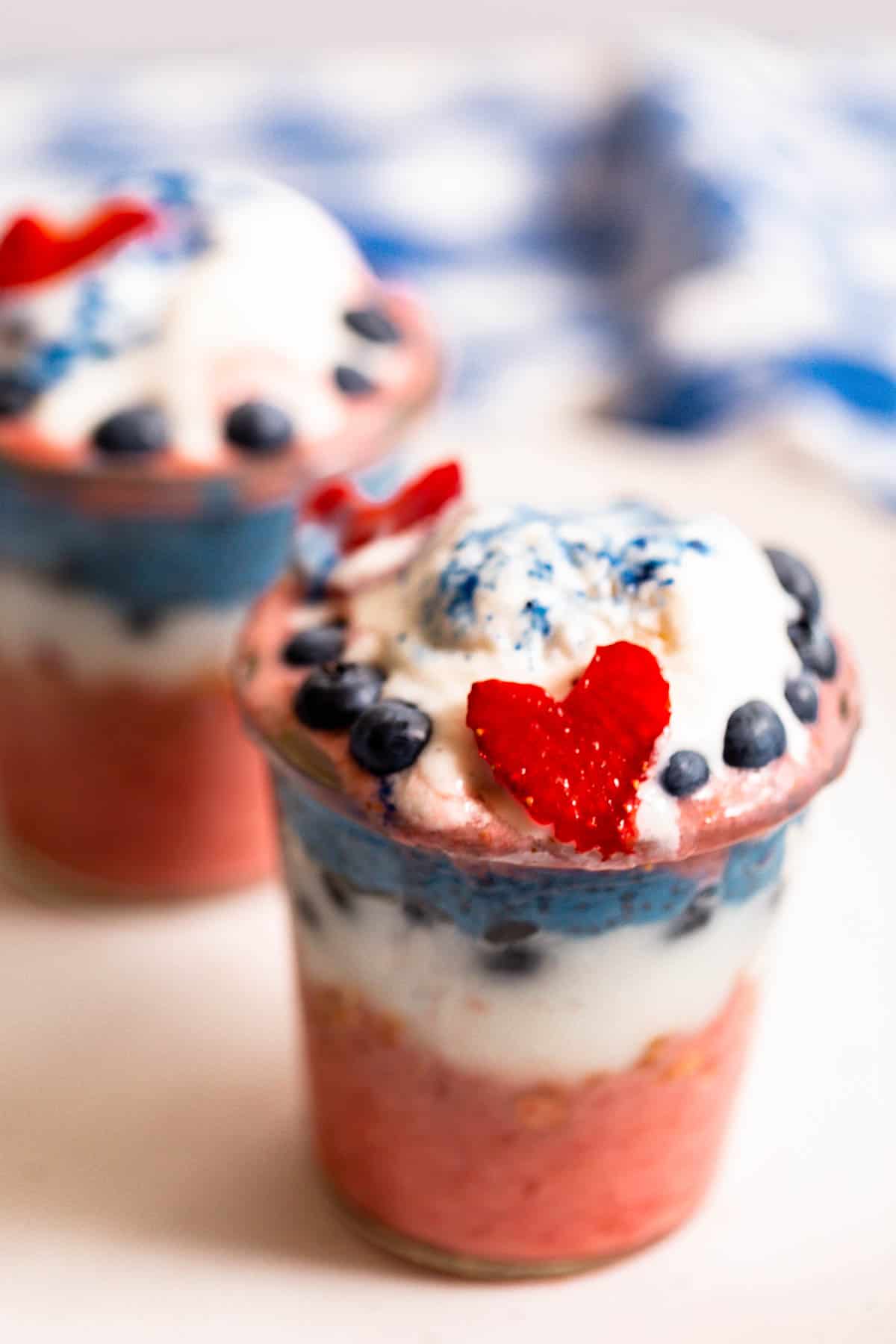Two naturally-colored red, white, and blue parfaits covered in blueberries and a strawberry heart.