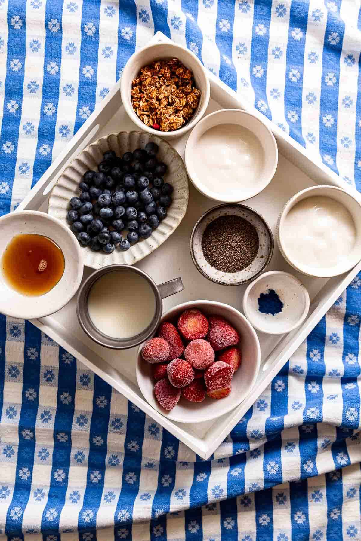A white square tray filled with red, white, and blue ingredients to make yogurt parfaits.