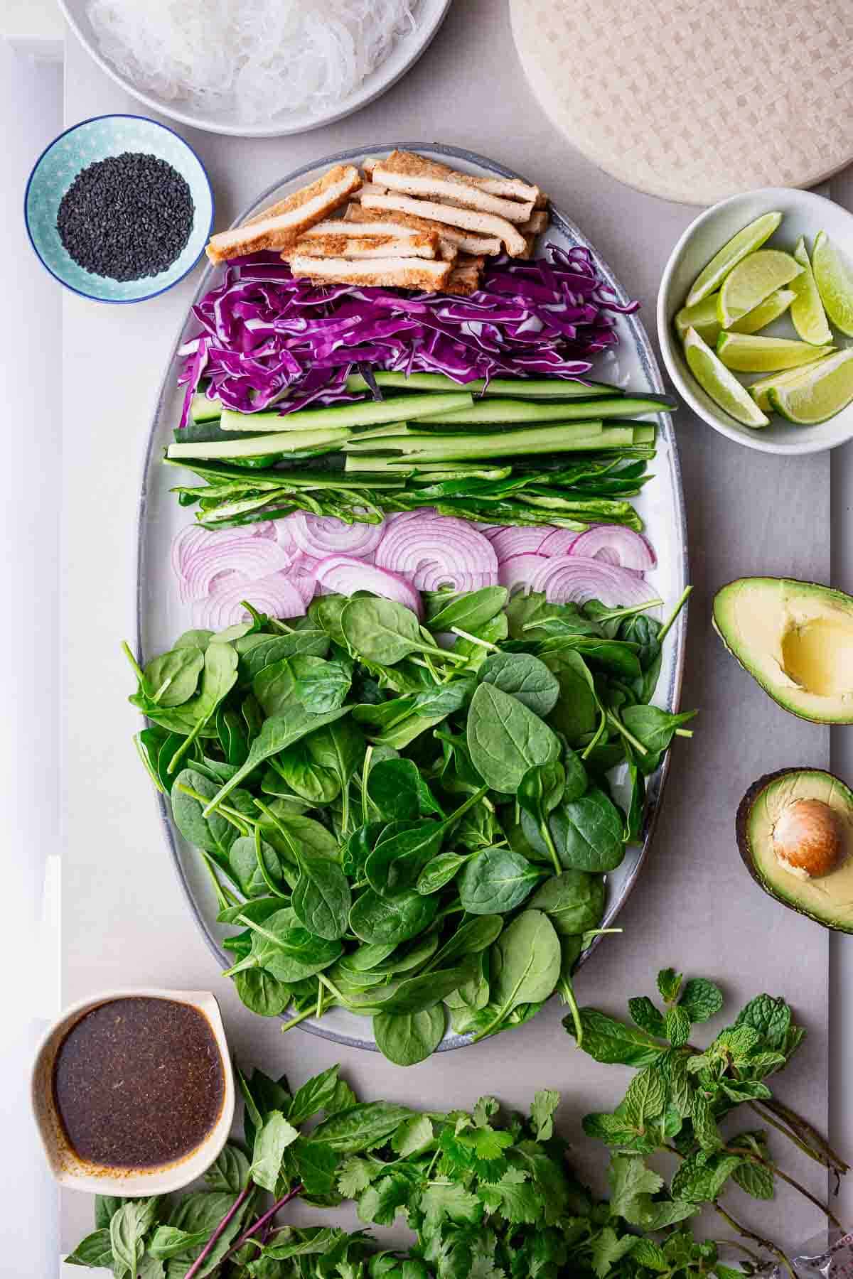 All the greens, purple cabbage, purple onion, noodles, tofu, and more that are used to make these green and purple summer rolls.