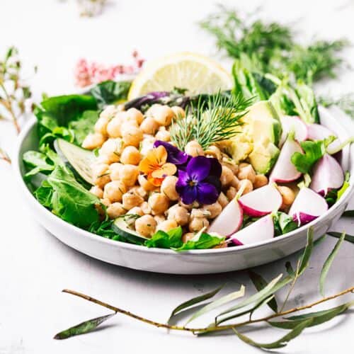 A colorful salad topped with vegan chickpea salad.