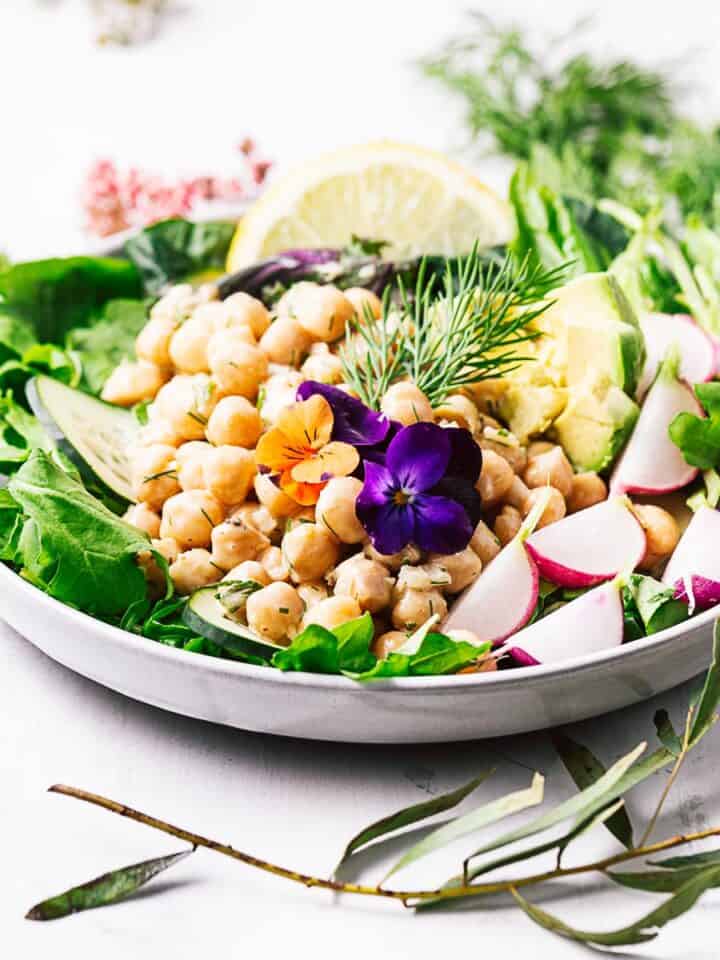 A colorful salad topped with vegan chickpea salad.