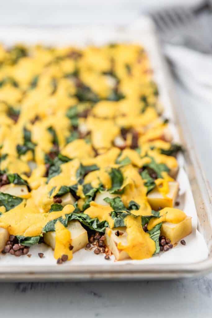 Cheesy roasted potatoes with greens and lentils on a sheetpan