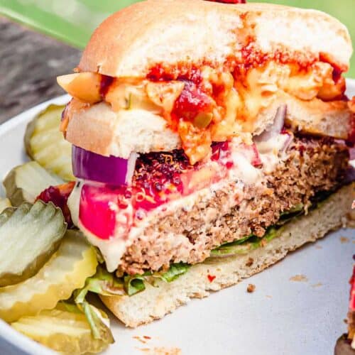 A closeup view of half a burger stacked with the works, including mac and cheese.