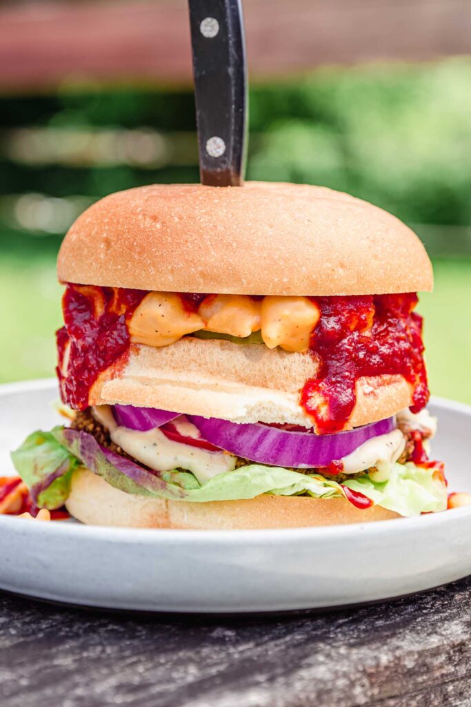 A burger with mac & cheese and bbq sauce in it.