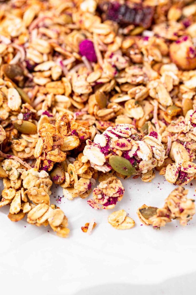 Homemade tropical granola scattered on white parchment paper.