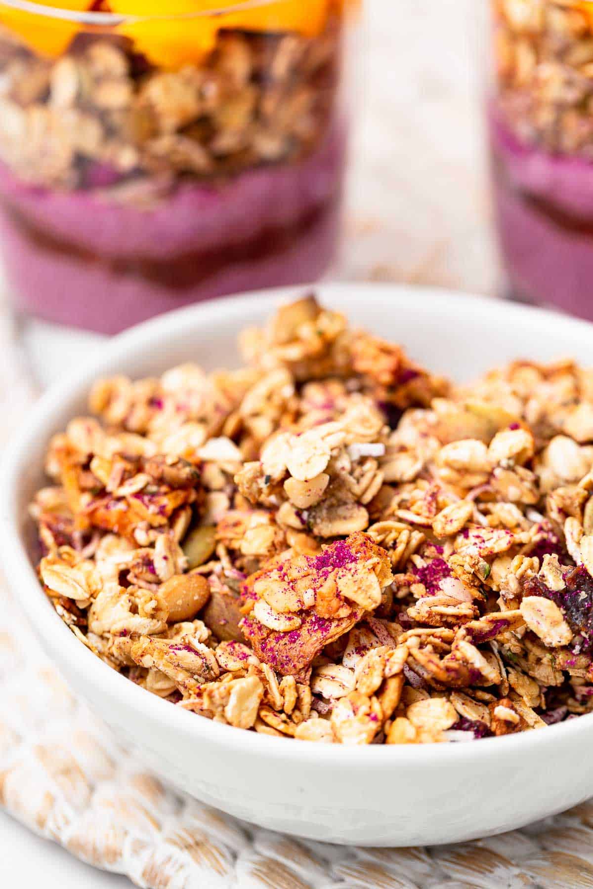 A bowl of homemade granola with pink pitaya powder running through it.