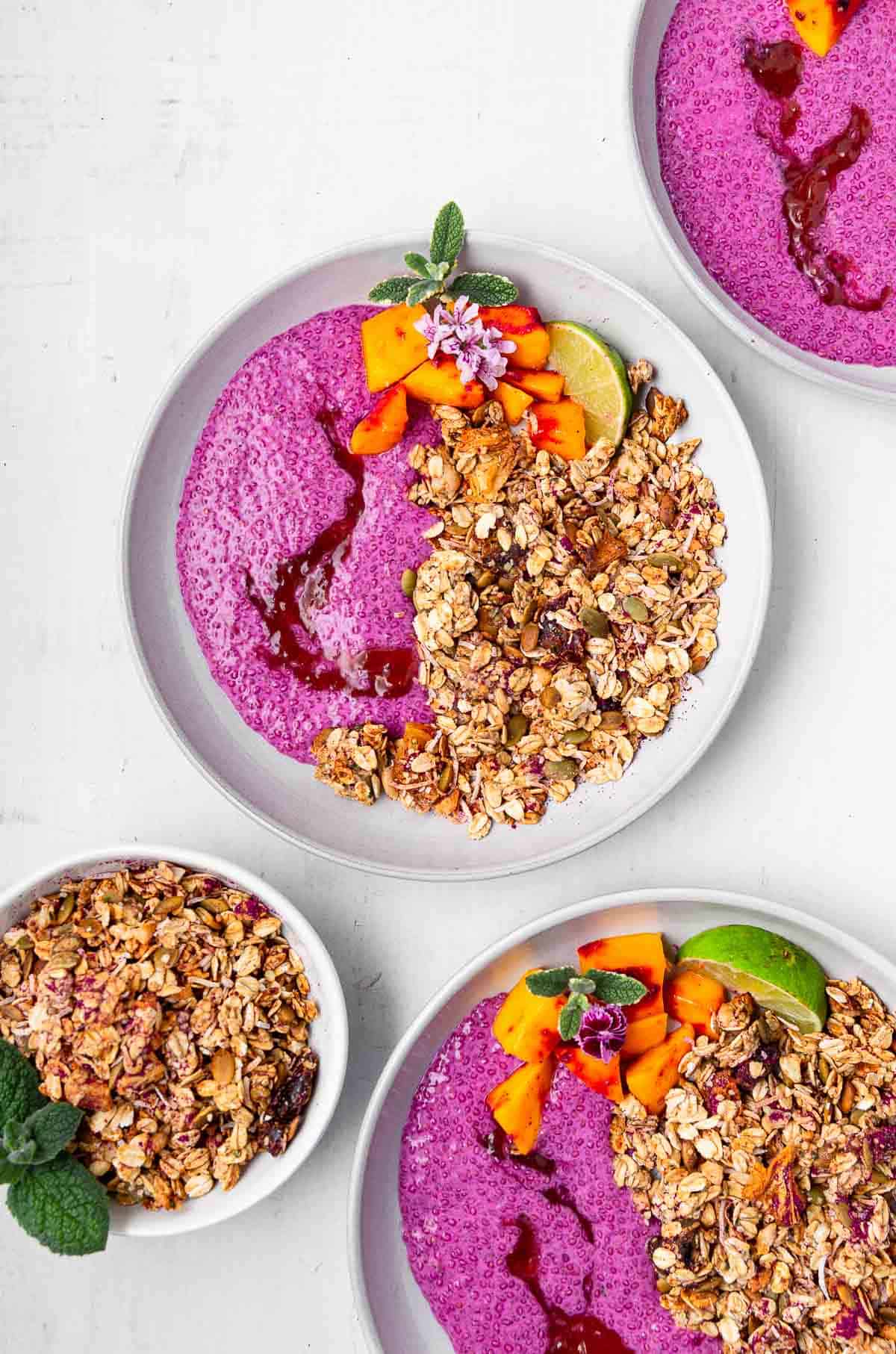 Tropical breakfast bowls filled with pink chia pudding and granola.