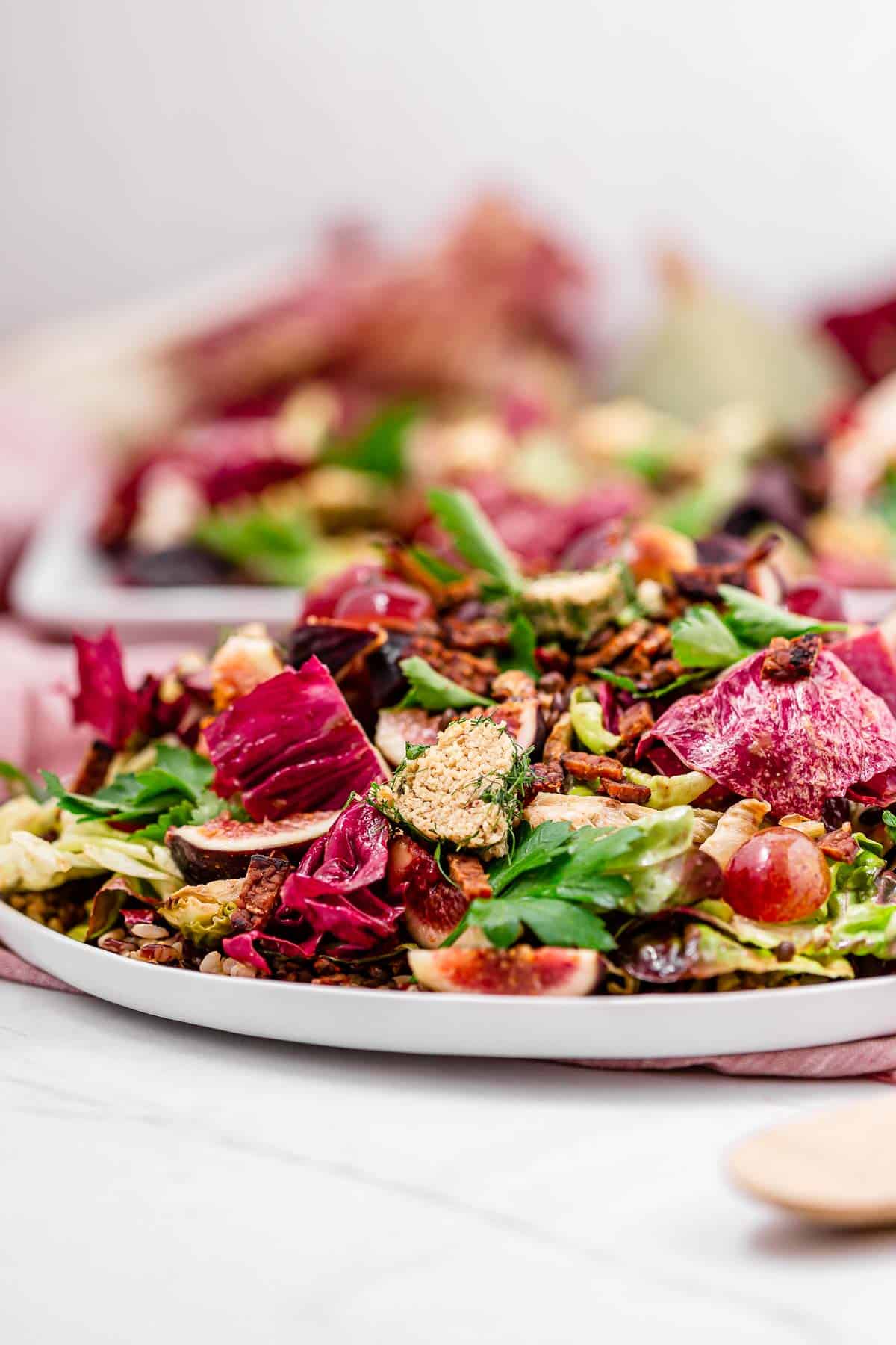 A side view of this vegan harvest salad, loaded with veggies, fruit, lentils, vegan bacon.