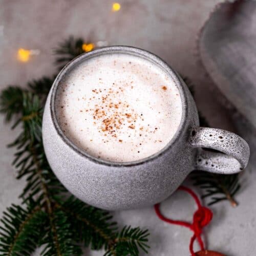 A big mug of vegan eggnog, surrounded by sparkly lights.