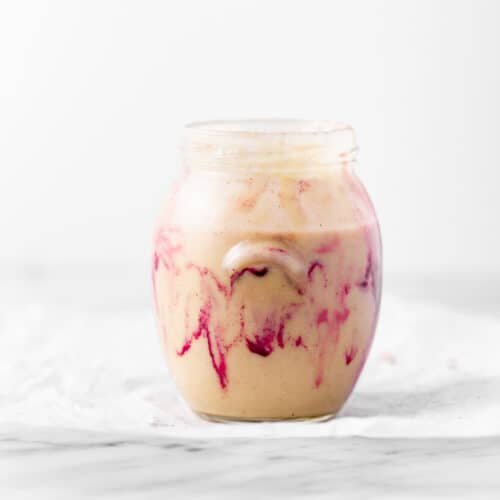 Homemade macadamia nut butter with pink swirls in a jar.