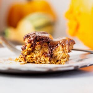 baked oatmeal with chocolate maple pecan topping plated with pumpkins surrounding