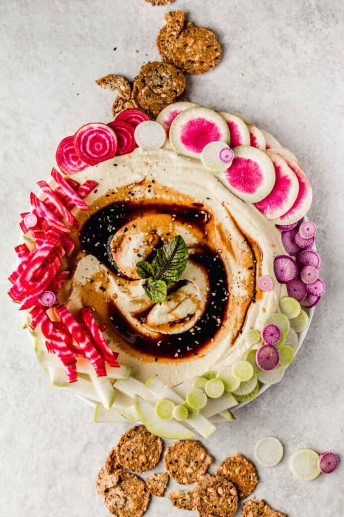 Smooth, creamy hummus topped with balsamic glaze and colorful veggie slices