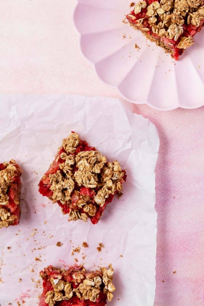 strawberry rhubarb bars on parchment and pink plates