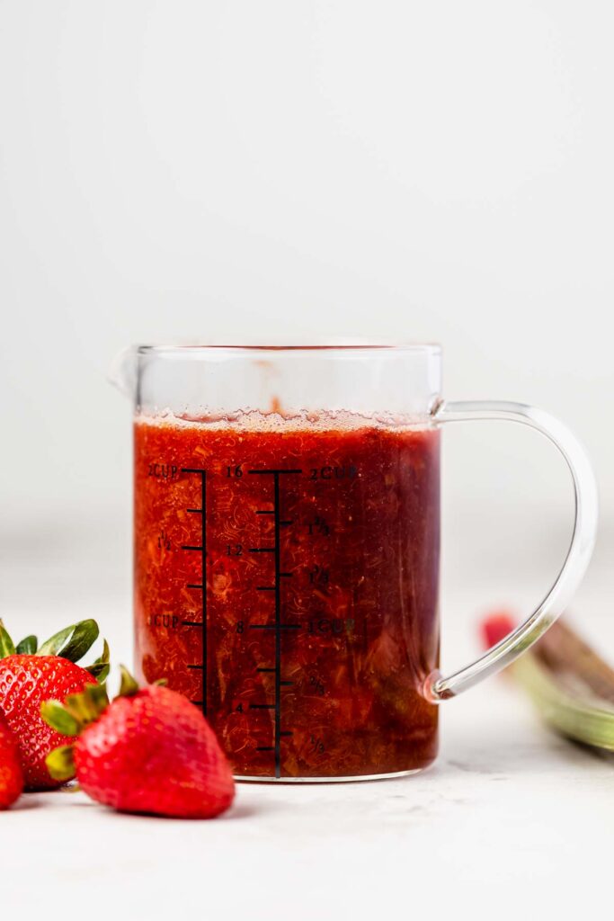 A glass measuring cup filled with strawberry rhubarb compote.