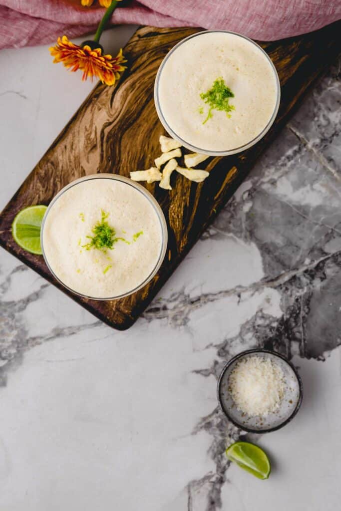 Bird's eye view of two Pina Colada cocktails topped with lime zest.