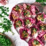 parsley surrounding a platter of radicchio leaves filled with hummus