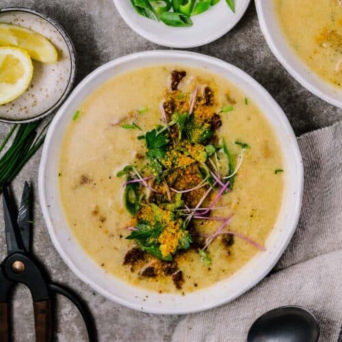a bowl of vegan oyster mushroom chowder with vegan bacon and other toppings