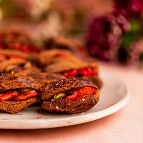 A closeup of a medjool date stuffed with freeze dried berries, cacao, and pistachios.