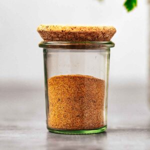 A jar of homemade french fry seasoning mix with a cork lid.