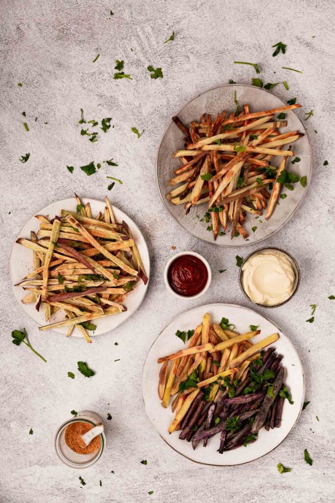 Three plates of french fries topped with parsley.