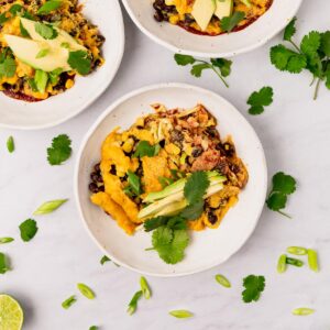 Three plates of vegan enchilada casserole.