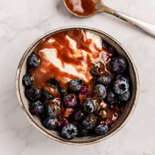 A bowl of berry porridge with fresh blueberries, yogurt, and homemade caramel sauce.