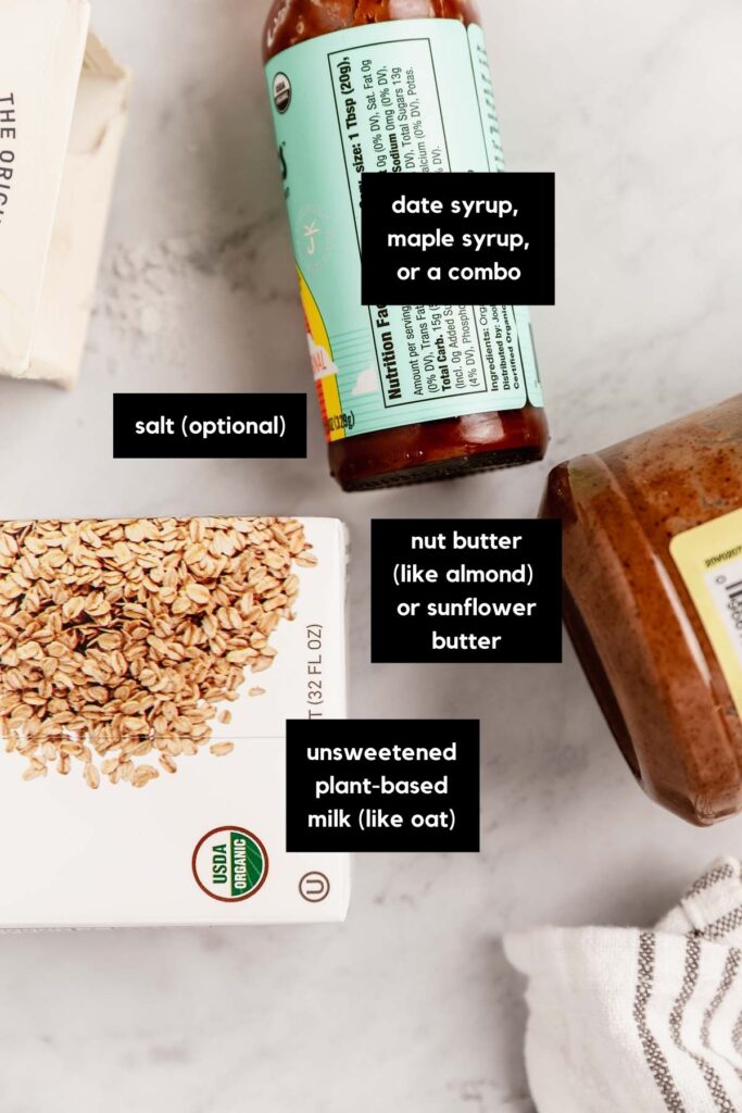 An overhead view of a jar of date syrup, flake salt, a box of oat milk, and a jar of almond milk.