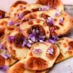 Air fryer sliced potatoes covered in chive blossoms.