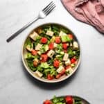 A bowl of salad with chunks of watermelon, avocado, cucumber, and tofu feta.