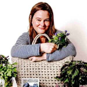 Kari hugging her market basket while surrounded by fresh produce.