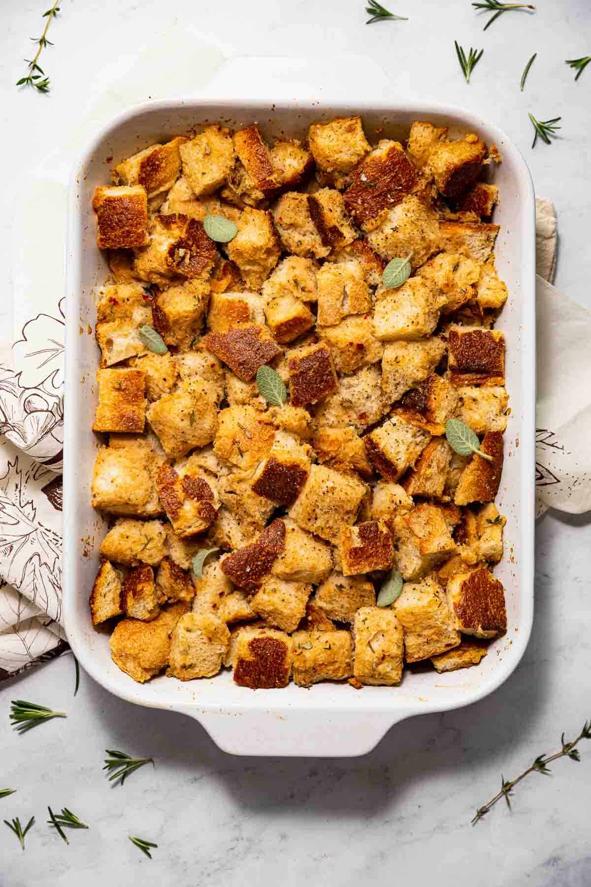 A 9x13 baking dish filled with simple baked sourdough stuffing with fresh herbs, a vegan Thanksgiving recipe.