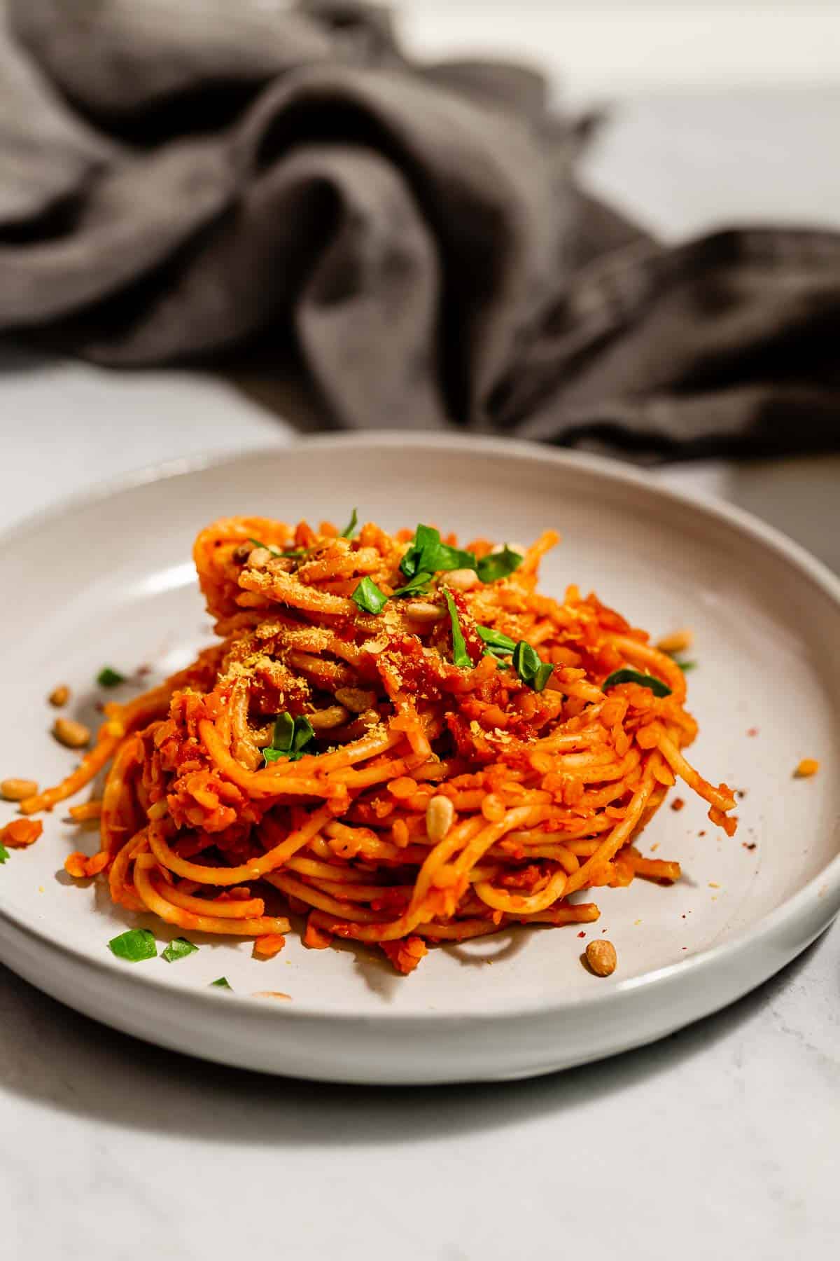 A side view of stacked red lentil bolognese spaghetti.