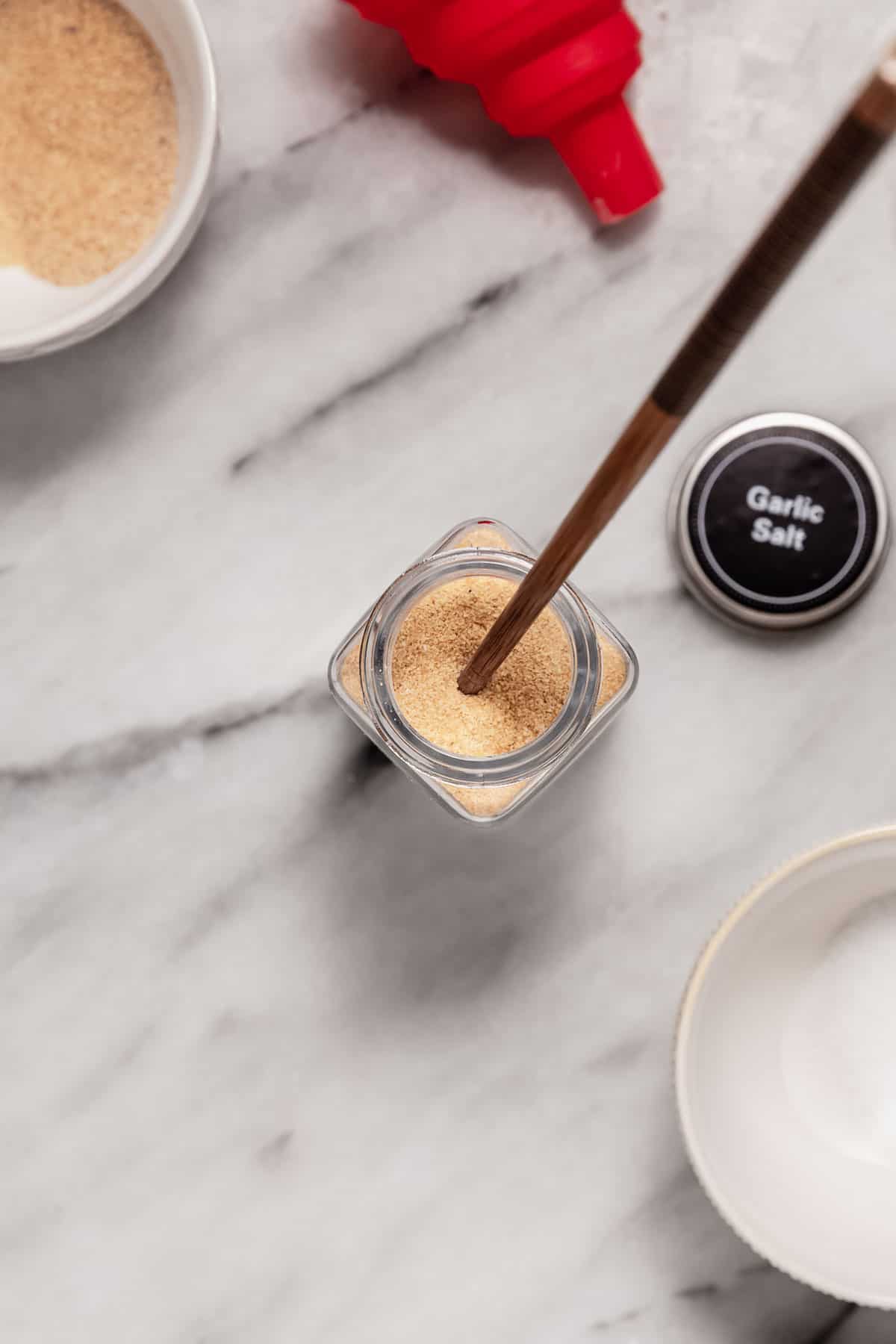 Using a chopstick to stir ingredients in a jar, making garlic salt.