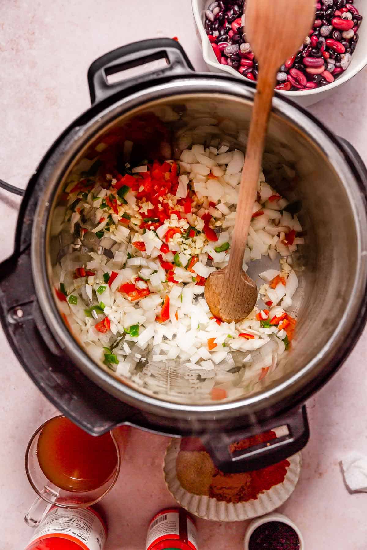 Sauteeing chopped ingredients in an Instant Pot for making vegan chili.