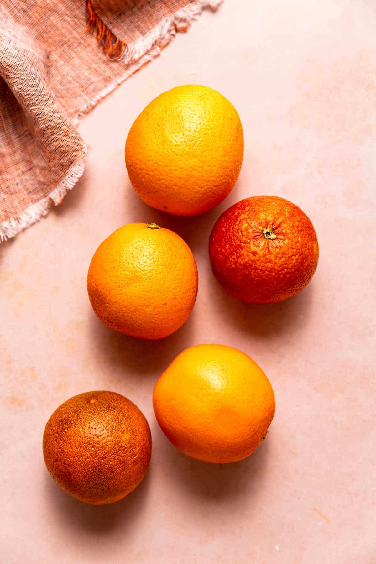 Three oranges and two blood oranges used to make blood orange ice cubes.