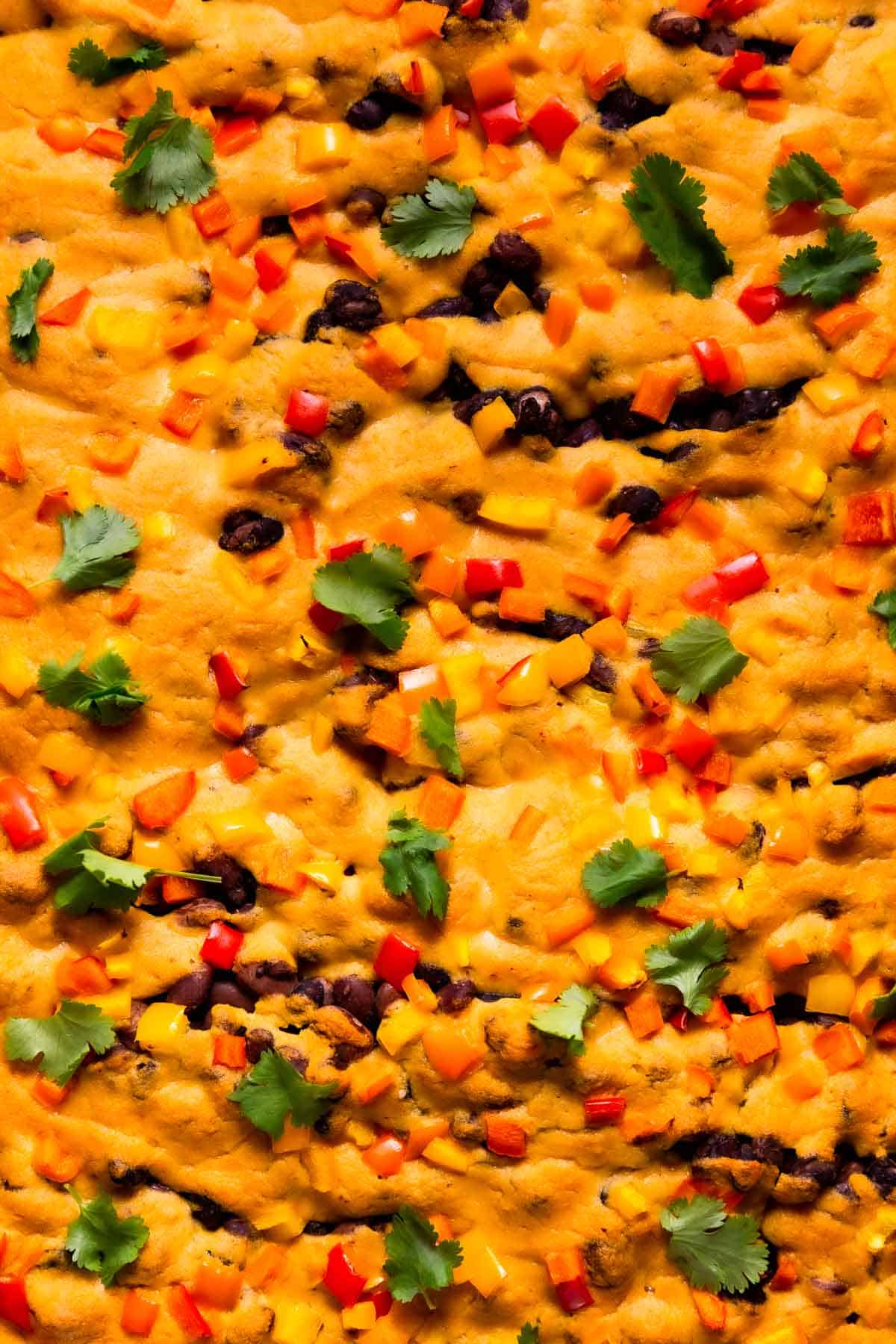 A closeup of plant-based queso on potato nachos.