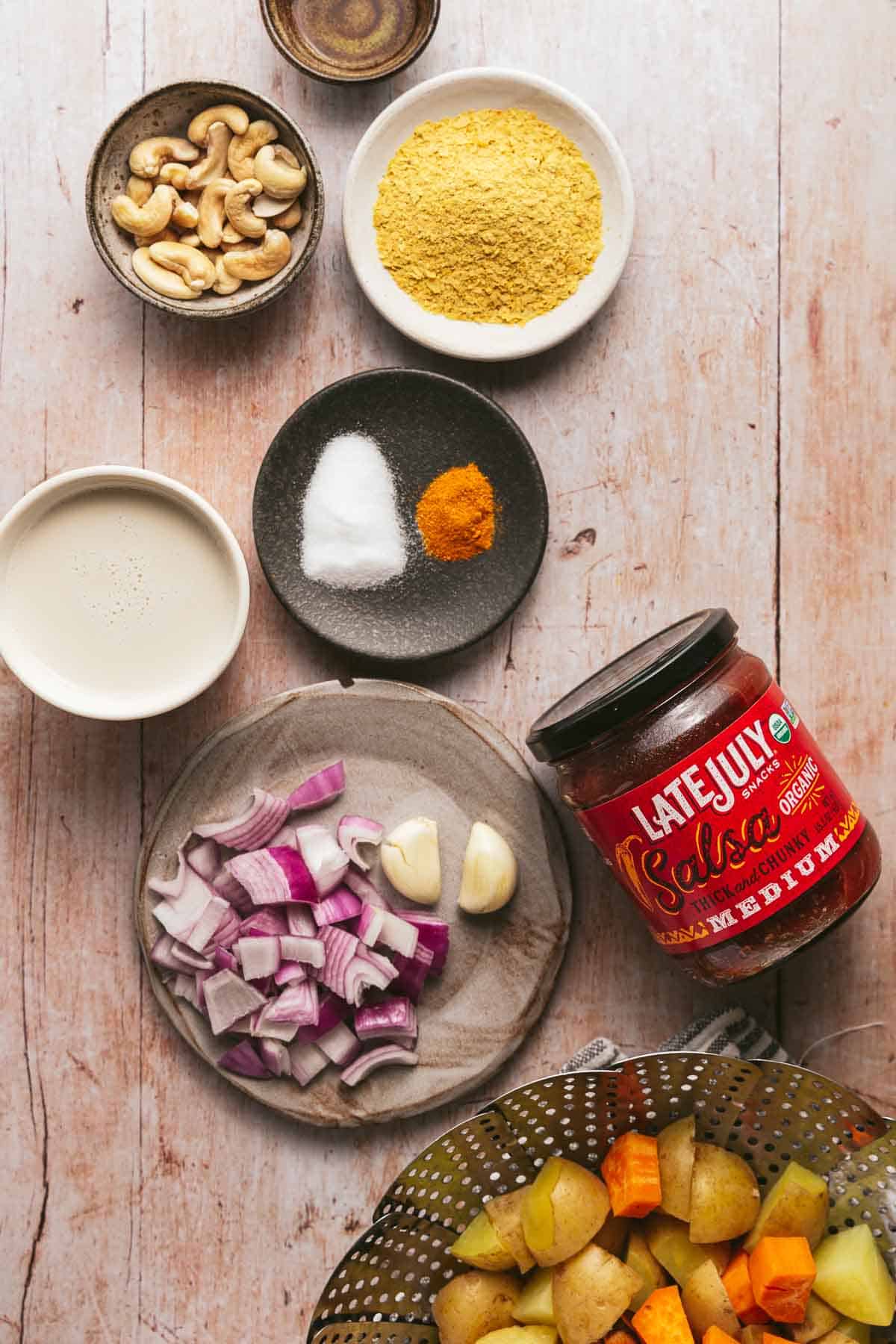 Ingredients for making plant-based queso on a wood background.