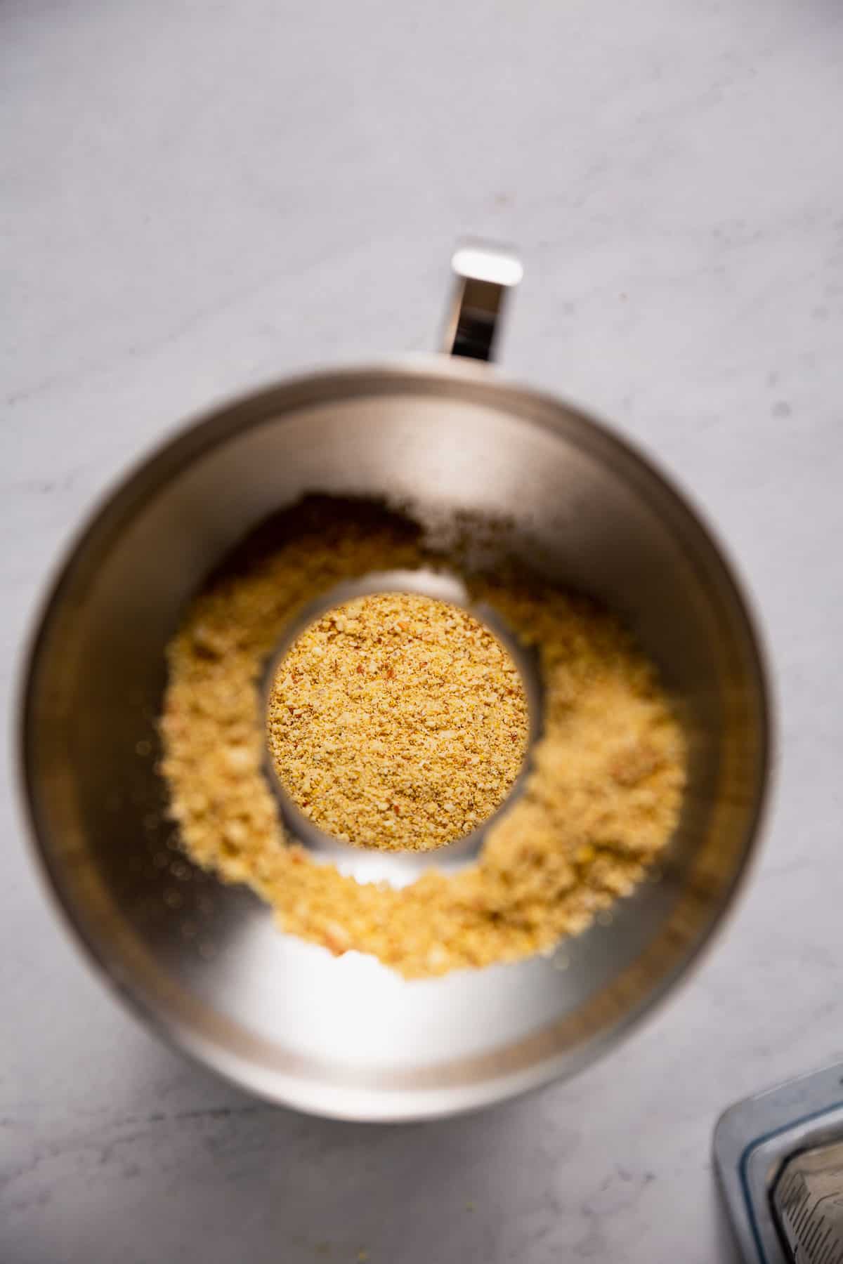 Pouring vegan parmesan sprinkles into a jar for storage.