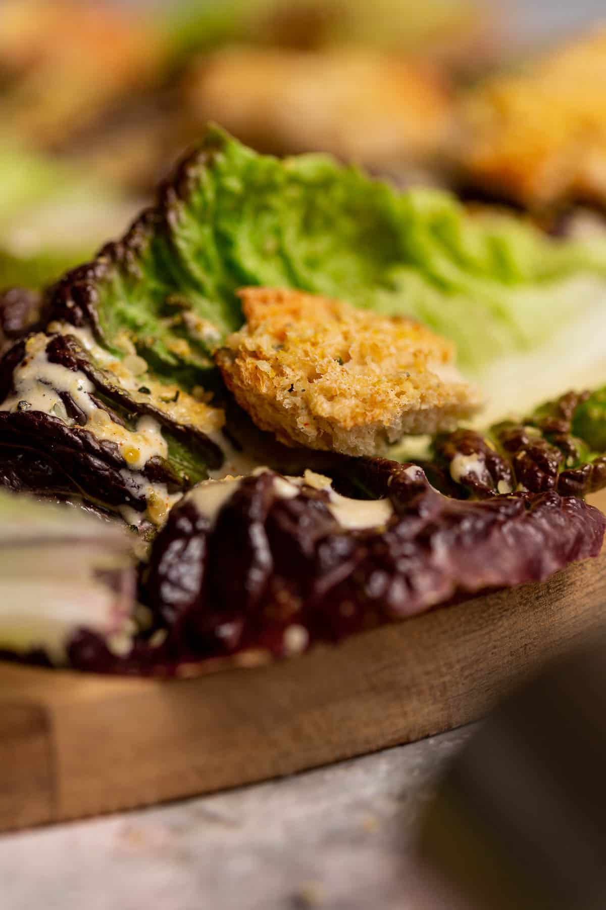 A closeup view of a sourdough crouton on a caesar salad.