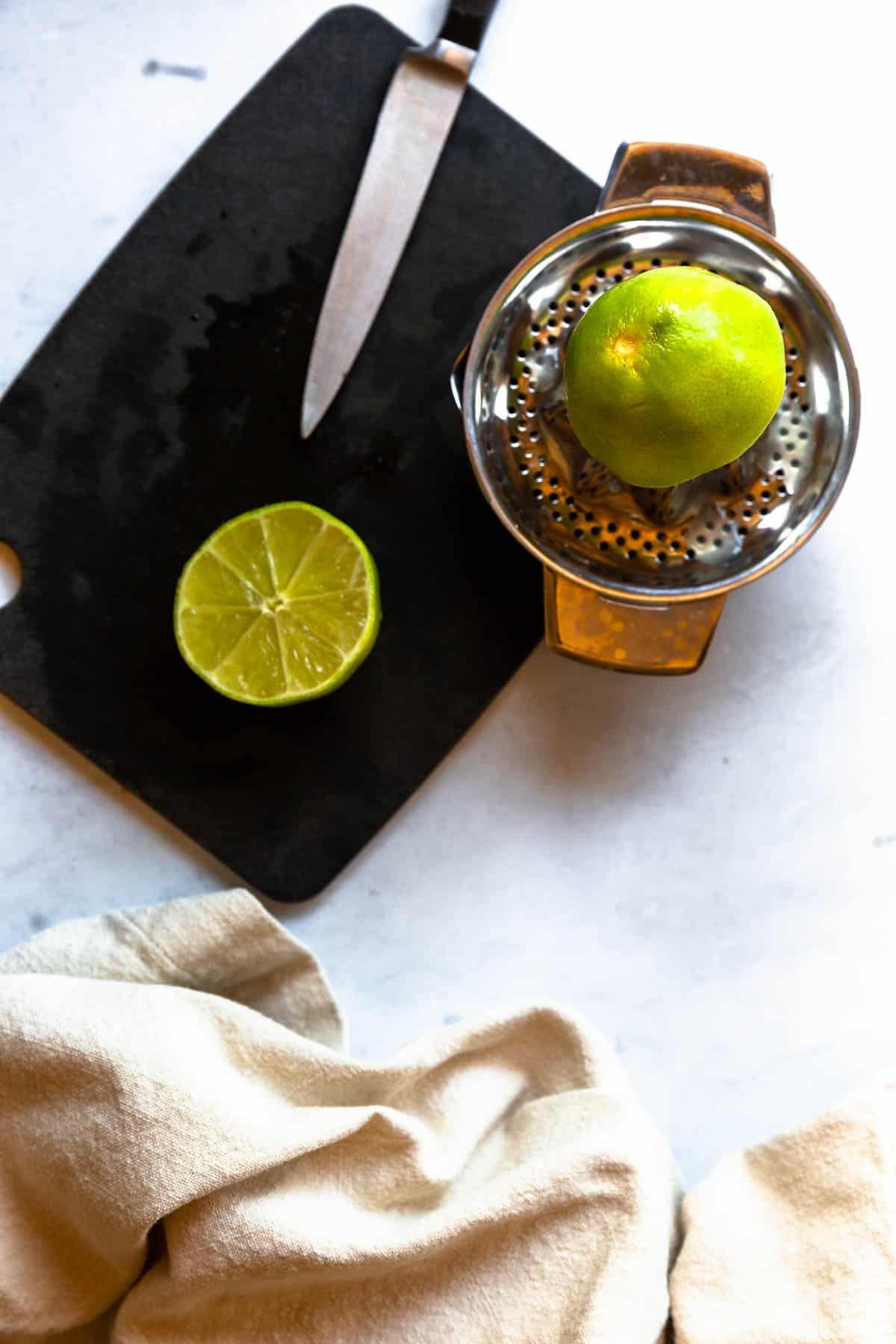 Lime sliced on a cutting board and on a juicer.