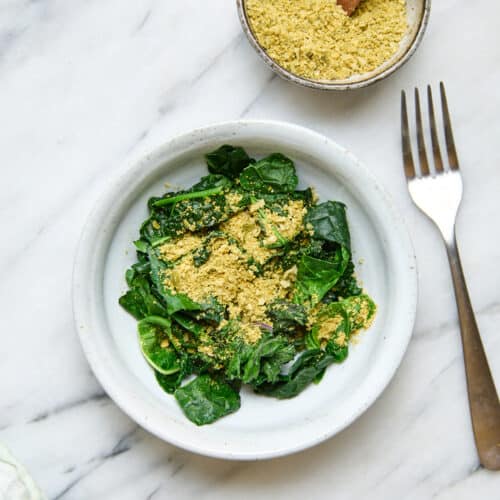 Vegan parmesan cheese that's nut-free on top of cooked greens.